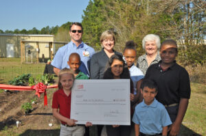 Left to Right: Archie Hogue, BJ's Wholesale Club AVP; Anne White, Step Up For Students VP of Operations, Organizational Development & Human Resources; and Temple Christian Academy Principal Jackie Pitts join Step Up For Students Scholarship recipients at the gardening event at Temple Christian Academy.