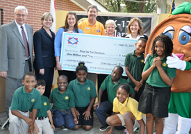 Seven Hills Academy principal Duwayne Baum (far left) joins representatives from Step Up For Students and Centennial Bank, scholarship recipient students, and "Penny," the bank mascot.
